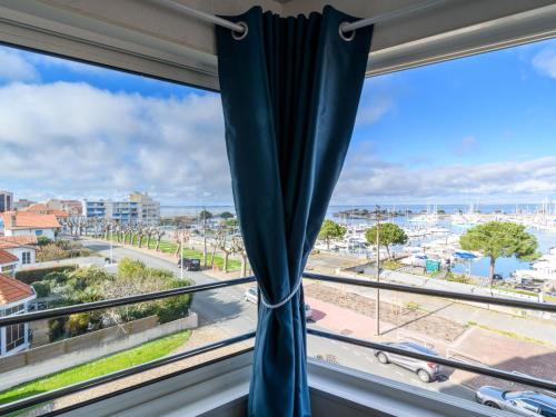 une fenêtre avec un rideau bleu donnant sur une ville dans l'établissement Apartment Grand voile by Interhome, à Arcachon