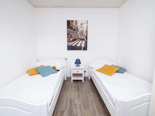 twee bedden in een kamer met witte muren en houten vloeren bij Apartment Nordstrand by Interhome in Norddeich