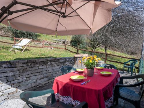 a table with a red table cloth and an umbrella at Holiday Home Baita Anita - DOD100 by Interhome in Murata