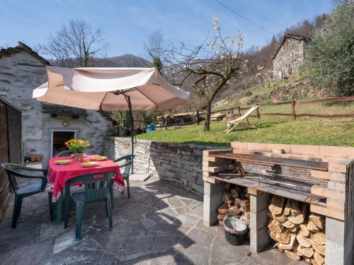 patio con tavolo, ombrellone e griglia di Holiday Home Baita Anita - DOD100 by Interhome a Murata