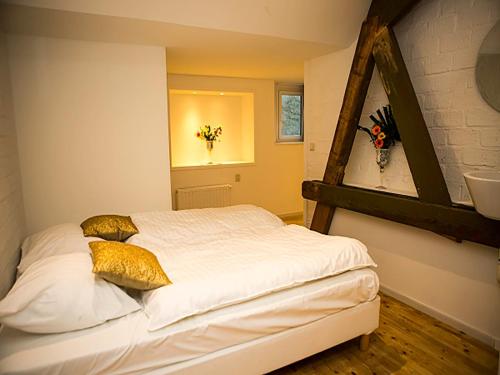 1 dormitorio con 1 cama con sábanas blancas y almohadas de oro en Holiday Home Bungalowpark Landsrade by Interhome, en Gulpen