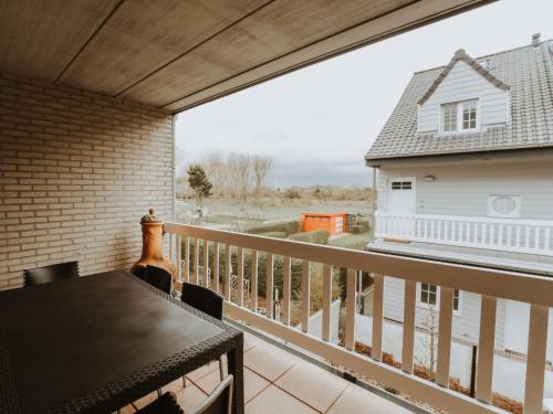 uma varanda com uma mesa e vista para uma casa em Apartment De Paddock-1 by Interhome em Bredene