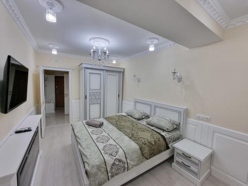 a white bedroom with a large bed and a chandelier at Premier Ultra Apartments Central in Chisinau in Chişinău