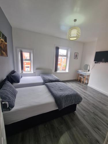 a large bedroom with two beds and a chandelier at Lovely 2-bedroom house close to Media City. in Manchester