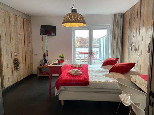 a bedroom with a bed with red pillows and a desk at Hotel Aan Zee in De Panne
