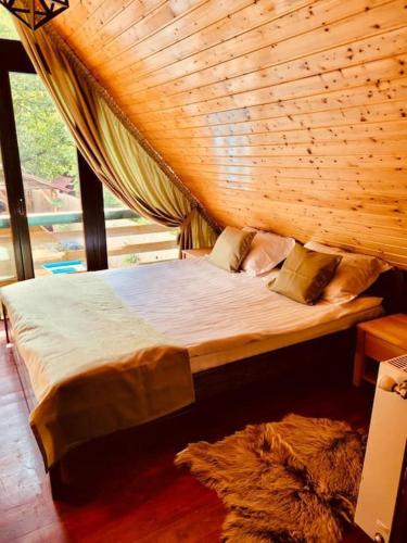 a bed in a room with a wooden ceiling at River House Transylvania in Frăsinet