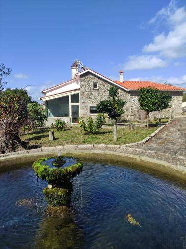 a pond with a bird bath in front of a house at Quinta de Esteves - Lake House Suites in Ponte de Lima