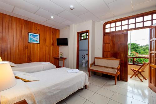 a hotel room with two beds and a chair at Hotel Villa Laguna in Puerto Ayora