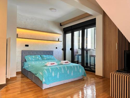 a bedroom with a bed with blue sheets and a television at Lexi Bombonjera apartman in Divčibare