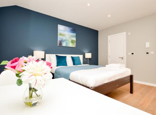 um quarto com duas camas e um vaso de flores em Fitzroy Serviced Apartments by Concept Apartments em Londres