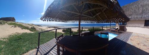 a resort with a pool and a straw umbrella at Khumbula iMozambique in Inhambane