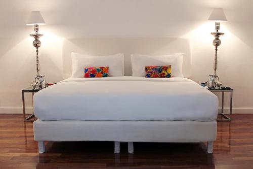 Palacio Julio Hotel في بوبلا: غرفة نوم بسرير ابيض ومصباحين