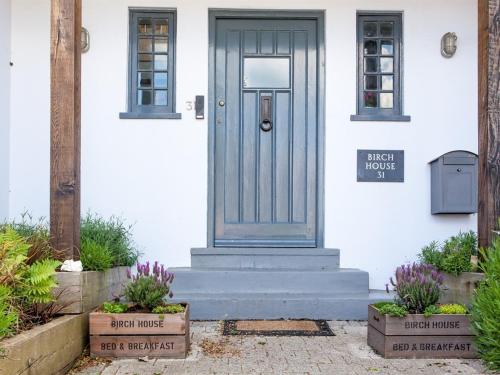 a blue door on a white house with plants at Birch House Bed & Breakfast in Weymouth