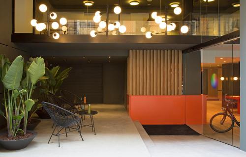 バルセロナにあるchic&basic Redingのオレンジの仕切りとテーブルと椅子が備わるオフィスロビー