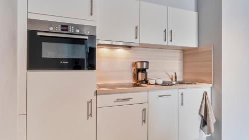 a kitchen with white cabinets and a stove top oven at Holiday Suites Blankenberge in Blankenberge