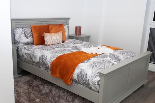 Luxurious MK Apartment-Campbell Park في ميلتون كينز: سرير عليه بطانية برتقال ومخدات