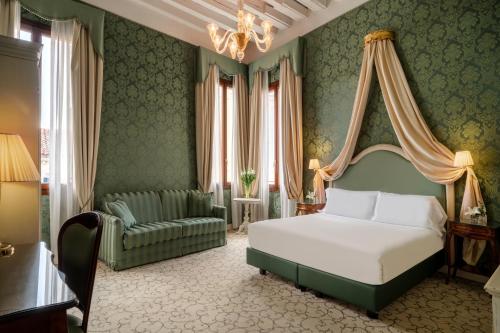 una camera con letto, divano e lampadario a braccio di Maison Venezia | UNA Esperienze a Venezia