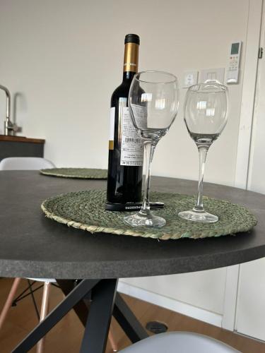 Una botella de vino y dos copas de vino en una mesa. en נס הבריאה, en Midreshet Ben Gurion