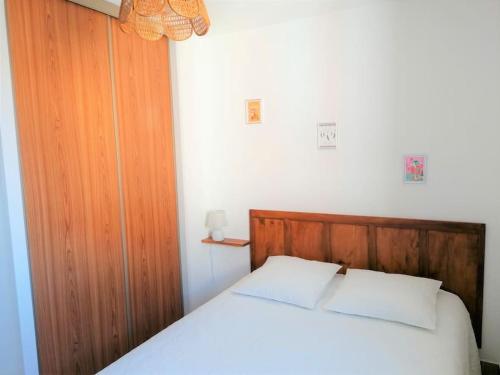 une chambre avec un lit blanc avec une tête de lit en bois dans l'établissement Appartement l'Evasion, vue mer, plages à pied, à Fréjus