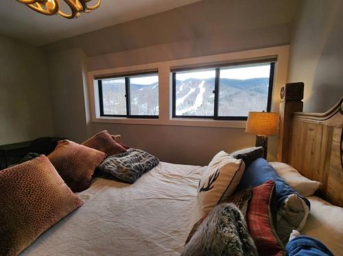 a bedroom with a bed with pillows and windows at White Mountain Vista! in Lincoln