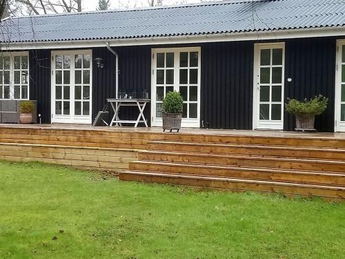una casa con una terraza de madera con una mesa. en Holiday Home Kaino - 700m from the sea in Sealand by Interhome, en Gilleleje