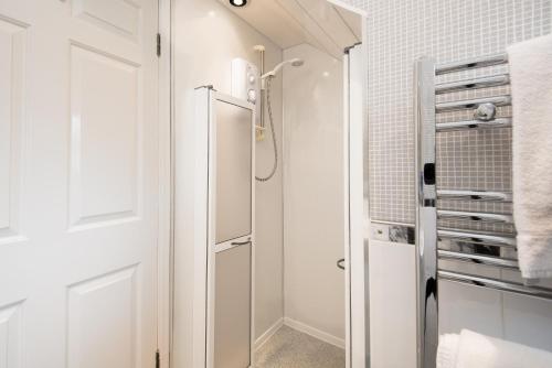 uma casa de banho branca com um chuveiro e uma porta de vidro em Morwick House B&B em Warkworth