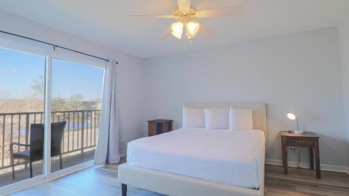 a white bedroom with a bed and a balcony at Oak Glen 84 in Ocean Springs
