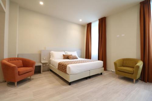 マリーナ・ディ・カッラーラにあるDoride Suites Boutique Hotelのベッド1台と椅子2脚が備わるホテルルームです。