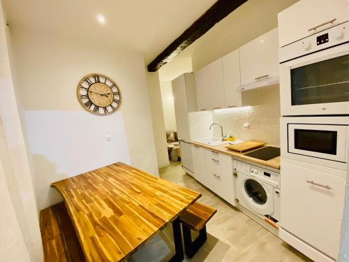 une cuisine avec une table en bois et une horloge au mur dans l'établissement VIEUX NICE - Families & Friends - 3 chambres - 6 personnes - 55 m2, à Nice