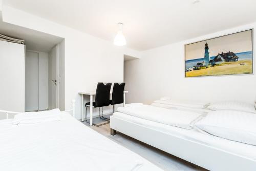 a white bedroom with two beds and a desk at Easy Apartments Work and Stay Cologne in Cologne