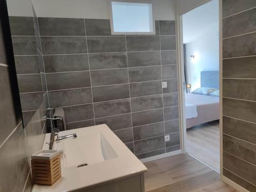 une salle de bain avec un lavabo et une chambre avec un lit dans l'établissement La Bastide de Gabin / ConciergerieDameCarcas, à Carcassonne