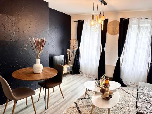 a living room with two tables and chairs and a black wall at Nordic Nest in Givet