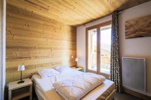 a bedroom with a wooden wall with a bed and a window at Residence Refuge du Golf - maeva Home in Flaine