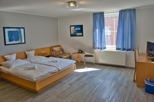 a bedroom with a bed and a desk and a television at Hotel Messeblick in Sarstedt