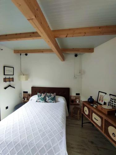 Schlafzimmer mit einem großen weißen Bett und Holzdecken in der Unterkunft Studio with furnished terrace at Riogordo in Ríogordo