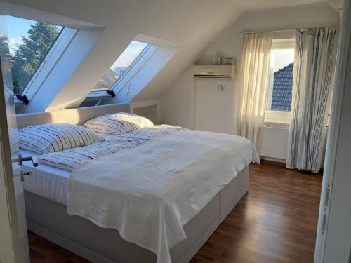 a bedroom with a bed with white sheets and windows at Studio - a79311 in Loxstedt