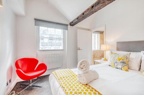 - une chambre avec un lit et une chaise rouge dans l'établissement Loft Piccadilly Circus Apartment, à Londres