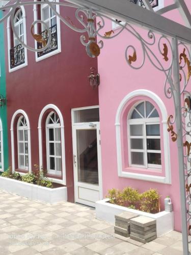 a pink building with a white door and windows at 波西塔諾villa民宿 全新旅店市中心 歐式別墅 親子住宿 in Xiaoliuqiu