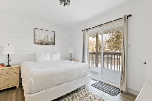 Un dormitorio blanco con una cama y un balcón. en Collingwood Chalet Near Blue Mountain Slopes 39A, en Collingwood