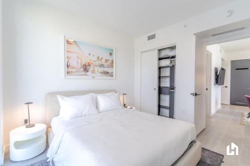 a white bedroom with a white bed and a table at Downtown Miami Condos by Lua Host in Miami
