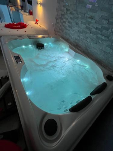 eine Whirlpool-Badewanne mit blauer Beleuchtung in einem Zimmer in der Unterkunft Love room avec spa privatif in Le Rove