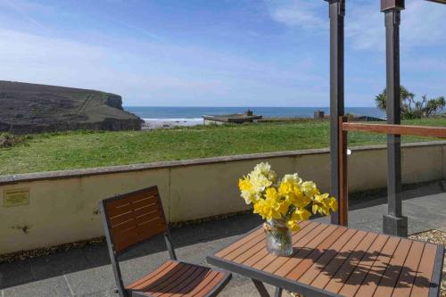 a table and a chair and a vase of flowers on a balcony at White Lodge Apartments in Mawgan Porth