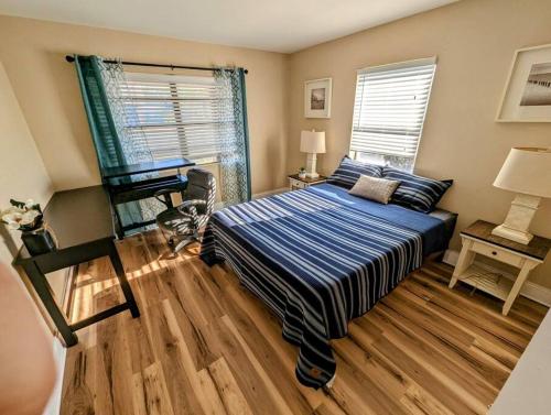 a bedroom with a bed and a desk and two windows at Modern & Comfy Lagoon Oasis - River Views - Parking in Titusville