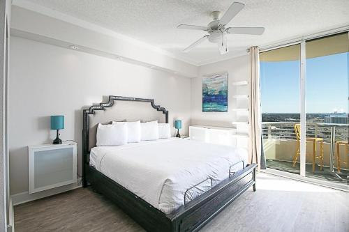 a white bedroom with a bed and a balcony at Ocean Club 1206 in Biloxi