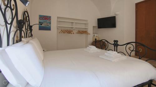 a bedroom with a white bed and a tv at Italianway - Piazza Campidoglio 3 in Lenno