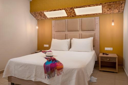 a bedroom with a white bed with a hat on it at Minos Boutique Hotel in Agia Galini