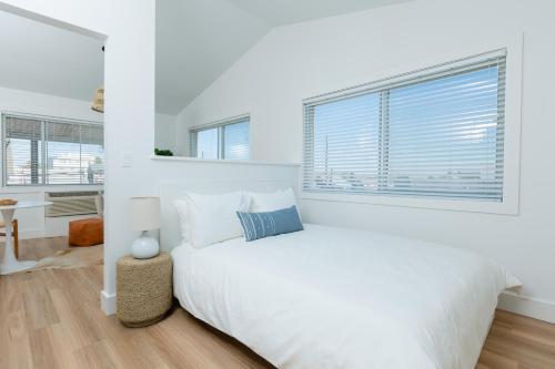 a white bedroom with a large bed and a window at DUNE Fairfield Beach in Fairfield