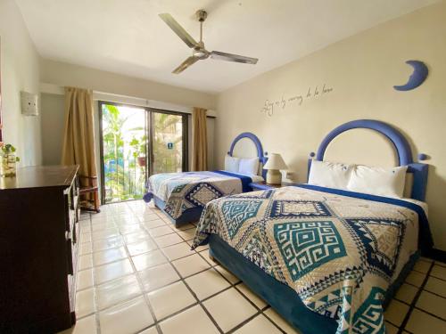 1 dormitorio con 2 camas y ventilador de techo en Puerto de Luna Pet Friendly and Family Suites, en Puerto Vallarta