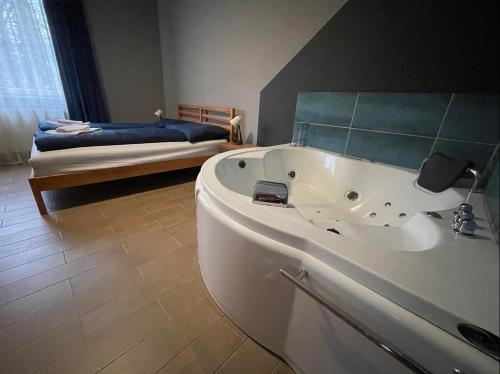 La salle de bains est pourvue d'une grande baignoire et d'un lit. dans l'établissement Tölgyfa Panzió, à Miskolctapolca
