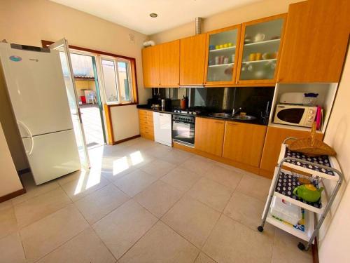 cocina con armarios de madera y nevera blanca en Mindelo Beach House en Vila Chã